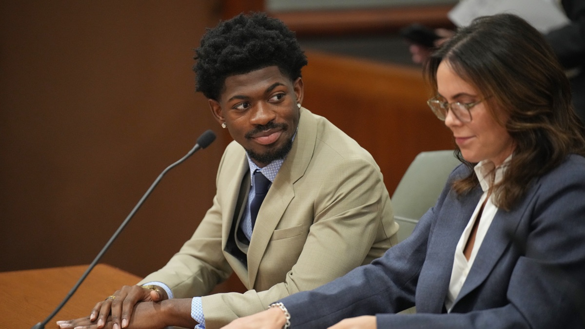 Lil Nas X seated at a court hearing beside another person.